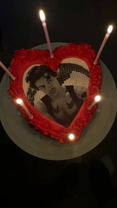 a heart shaped cake with candles in the shape of a photo and two people on it