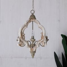 an old chandelier hanging from a chain in front of a white painted wall