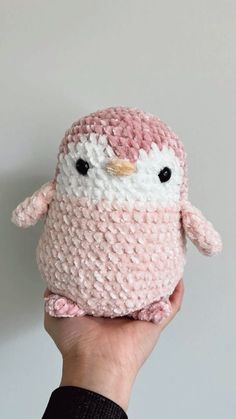 a hand holding a pink and white crocheted owl