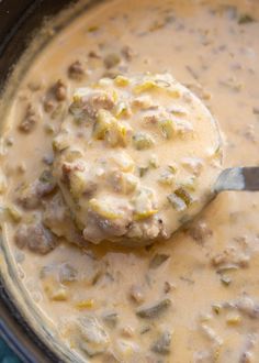 a ladle full of soup with meat and vegetables in it, ready to be eaten