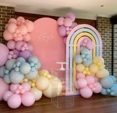 an arch is decorated with balloons and pastel colors