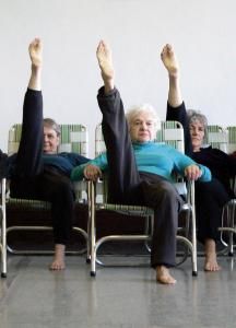 three older people sitting in chairs with their feet up and one person laying on the ground