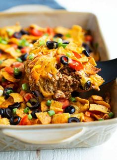 a casserole dish with tortilla chips and black olives