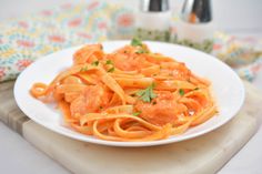 a white plate topped with pasta covered in sauce and garnished with parsley