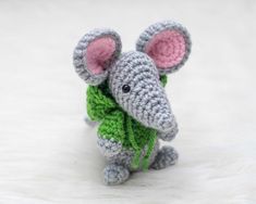 a small crocheted mouse with a green scarf around it's neck sitting on a white surface