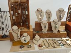 a table topped with lots of necklaces and jewelry on top of wooden trays