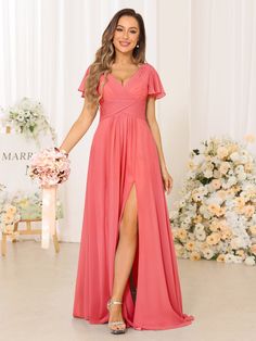 a woman standing in front of a flower display wearing a pink dress with short sleeves and thigh high slit