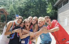 a group of young people standing next to each other in front of a wooden building