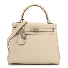 This is an authentic HERMES Togo Kelly Retourne 25 in Craie. This iconic handbag is expertly handcrafted of grained calfskin leather in off white. The bag features rolled leather top handles, a short front flap with a strap closure, and palladium plated hardware including a padlock and keys. The top flap opens to a matching goatskin leather interior with zipper and patch pockets. Hermes Kelly Retourne, Hermes Crossbody Bag, Hermes Bags, Leather Interior, Leather Top, Patch Pocket, Calf Skin, Dust Bag, Shoulder Strap