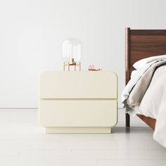 a white bed sitting next to a nightstand on top of a hard wood floor