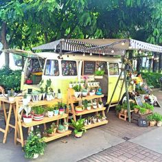 an old vw bus is covered in potted plants and other things for sale