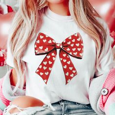 a woman wearing a white shirt with red hearts on it and a big bow at the front