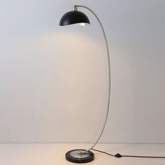 a floor lamp that is on top of a white table with a black light bulb