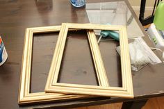 three wooden frames sitting on top of a table next to a can of water and a blow dryer