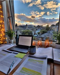 an open laptop computer sitting on top of a wooden desk next to a book and pen