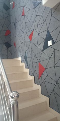 a stair case next to a wall with red and black triangles painted on the side