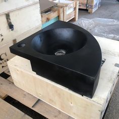 a large black sink sitting on top of a wooden box in a room filled with boxes