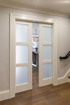 an open white door leading to a dining room and living room with wood flooring