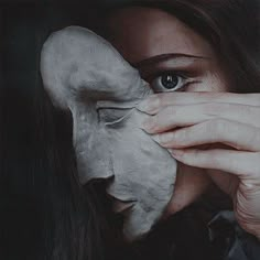 a woman covering her face with a white mask over her eyes and the other half of her face