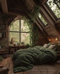 an attic bedroom with large windows and green comforter on the bed, surrounded by greenery