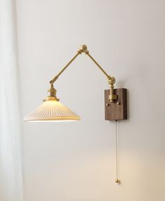 a wall light with a wooden arm and white glass shade hanging from it's side