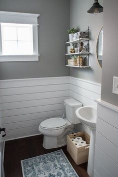 a white toilet sitting next to a sink in a bathroom under a mirror and light fixture