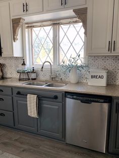 a kitchen with white cabinets and gray counter tops, an open dishwasher in the middle