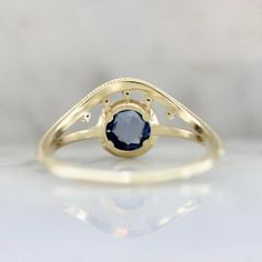 a yellow gold ring with a blue sapphire stone in the center, on a white surface