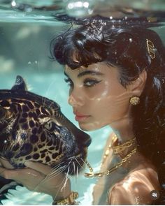 a woman holding a leopard in her hand under the water with it's mouth open