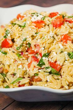 a white bowl filled with pasta salad on top of a wooden table