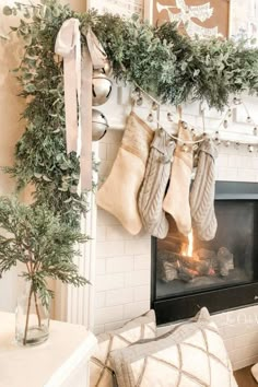 stockings hung on the mantle in front of a fireplace with christmas decorations and greenery