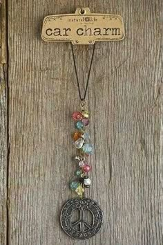 a peace sign hanging from the side of a wooden door with charms attached to it