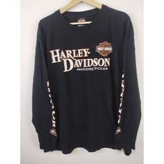 the harley davidson long sleeve shirt is hanging on a hanger in front of a white wall