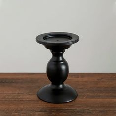 a black candle holder sitting on top of a wooden table