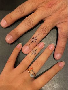 two fingers with tattoos on them, one has an arrow and the other has a star