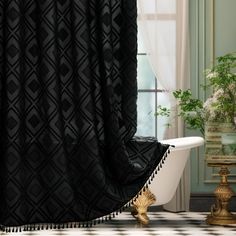 a bath tub sitting next to a window covered in black and white shower curtaines