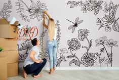 two people are painting a wall with flowers