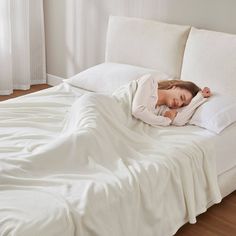 a woman sleeping on top of a white bed