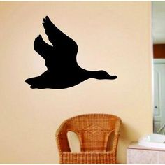 a black bird flying in the air next to a bathroom wall decal on a beige wall