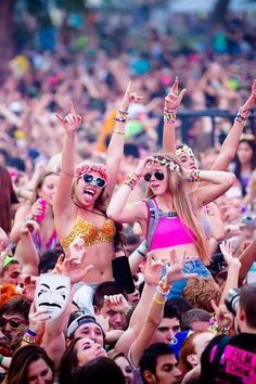 a woman is standing in the middle of a crowd with her arms up and hands raised