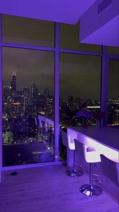 a room with two bar stools and a view of the city at night