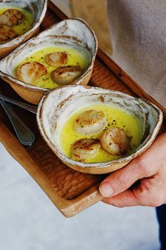 three bowls filled with food on top of a wooden tray