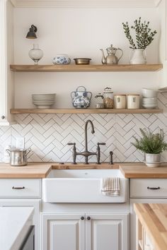 a kitchen with white cabinets and open shelves on the wall above the sink is filled with dishes