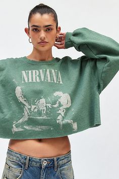 Vintage-inspired crew neck pullover featuring Nirvana graphics across the front & left sleeve. Designed in a slouchy, cropped fit featuring a crew neckline, drop shoulder long sleeves and a raw-edge hem. Exclusively at Urban Outfitters. Features Nirvana graphic cropped crew neck pullover Graphic pullover sweatshirt Soft brushed knit Crew neckline and long balloon sleeves Nirvana graphics across the front & sleeve Slouchy, boxy fit Cropped length Easy pull-over style Content + Care 100% Cotton Machine wash Imported Size + Fit Model in Green is 5’9.5" and wearing size Small Measurements taken from size Small Chest: 46" Length: 16" | Nirvana Graphic Cropped Crew Neck Pullover Top in Green, Women's at Urban Outfitters Graphic Pullover, Band T Shirts, Long Balloons, Music Band, Tees For Women, Small Chest, Classic Rock, Balloon Sleeves, Nirvana