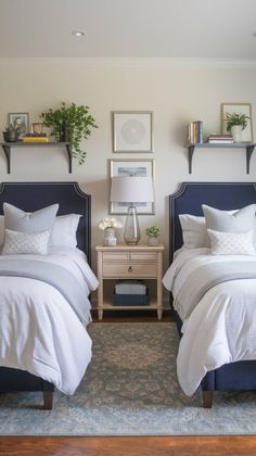 two beds in a bedroom with white sheets and pillows