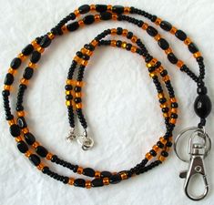 Orange & Black Beaded Lanyard This Orange & Black Beaded Lanyard can be used as a badge holder, an I.D. holder, keychain necklace, watch holder - it's a multi-use accessory for home or office! 34" in length, long enough to put on or remove overhead. It also has an easy-to-use metal lobster clasp for your convenience. It's made with orange and black glass beads and strung on strong C-Lon beading cord. Snap-on badge holder, clip, and keyring are included to keep your badges or keys ready when you Everyday Black Beaded Jewelry, Adjustable Black Lanyard With Key Clip, Adjustable Black Lanyards With Key Clip, Black Beaded Adjustable Lanyards, Adjustable Black Badge Holder With Key Leash, Handmade Black Lanyards, Black Beaded Lanyard As Gift, Black Beaded Lanyards As Gift, Black Beaded Lanyards For Gift