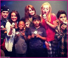 a group of young people standing next to each other holding ice cream cones in their hands