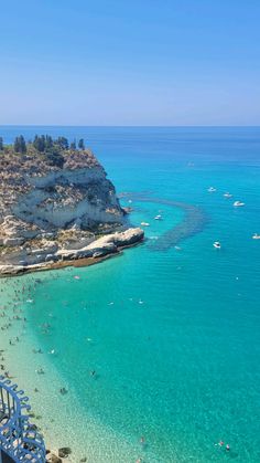 people are swimming in the clear blue water at an ocean beach on a sunny day