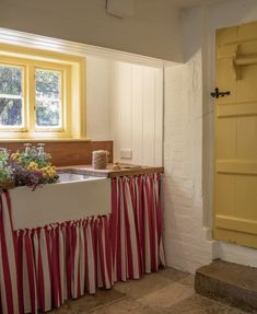 a kitchen with yellow and red curtains on the window sill, sink and counter