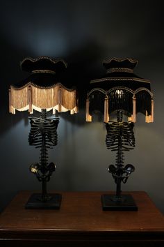 two lamps that are sitting on top of a wooden table in front of a black wall